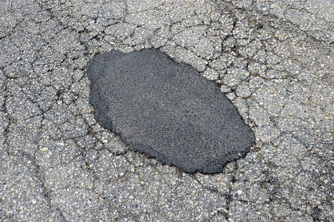 cracked asphalt road surface and repair patch concrete